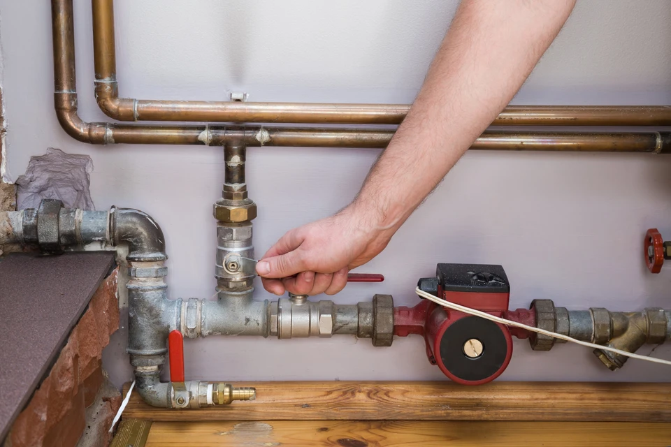 Homme travaillant sur un radiateur près d'une fenêtre dans un intérieur résidentiel moderne