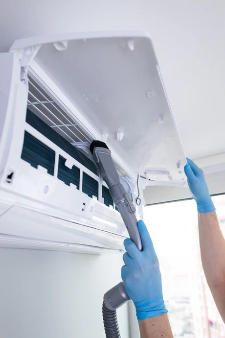 Un électricien-chauffagiste professionnel travaillant sur l'installation d'une pompe à chaleur intérieure dans une maison moderne, effectuant les connexions électriques et les branchements techniques. Le professionnel est concentré sur son travail, portant des vêtements de travail professionnels et des gants de protection, montrant le sérieux et l'engagement dans la réalisation de l'installation. La scène doit transmettre la compétence technique et la proximité avec le client dans un environnement résidentiel confortable.