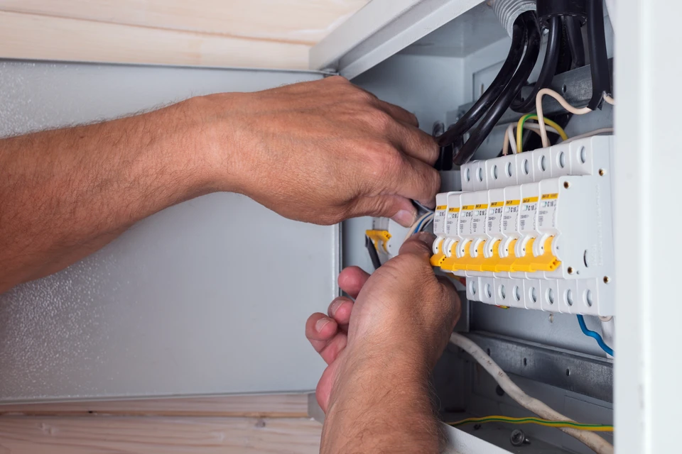 Ingénieur électrique utilisant un équipement de mesure pour vérifier la tension du courant électrique à l'aide d'un disjoncteur et d'un système de câblage pour l'entretien dans la carte principale de distribution d'énergie