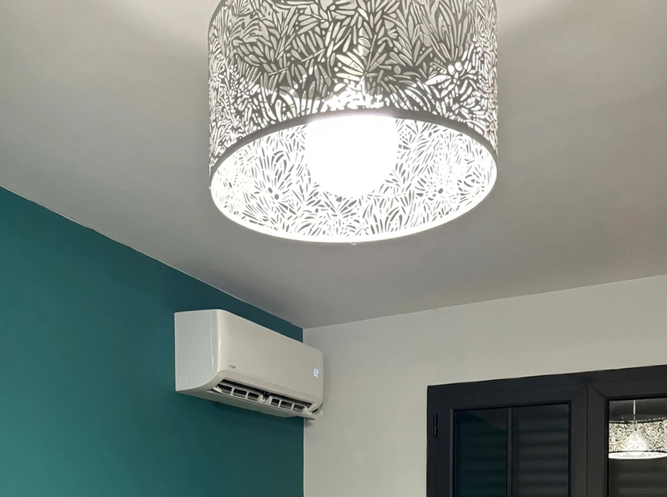 Une personne réchauffe ses mains au-dessus d'un radiateur blanc dans un intérieur domestique aux murs clairs