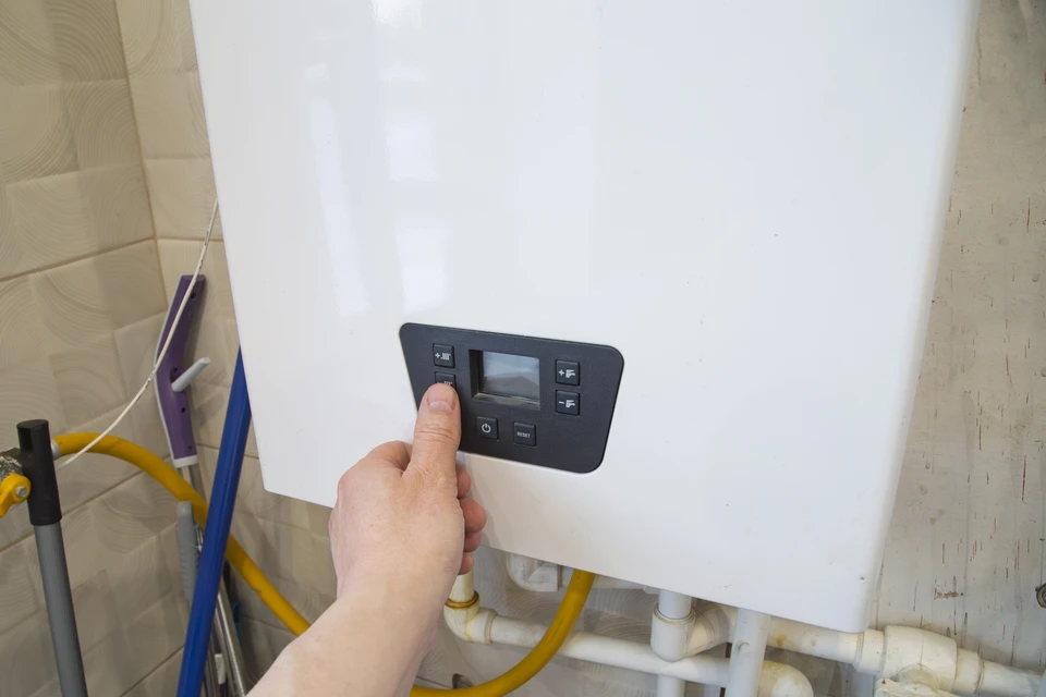 Artisan en v&ecirc;tement de travail professionnel &eacute;quip&eacute; d'outils, positionn&eacute; entre deux &eacute;l&eacute;ments&nbsp;: d'un c&ocirc;t&eacute; une armoire &eacute;lectrique murale ouverte montrant des installations &eacute;lectriques r&eacute;sidentielles, de l'autre c&ocirc;t&eacute; une pompe &agrave; chaleur ou un syst&egrave;me de chauffage domestique. L'artisan regarde l'appareil photo avec une expression professionnelle confiante. La sc&egrave;ne se d&eacute;roule dans un environnement int&eacute;rieur r&eacute;sidentiel clair et moderne. Cette composition doit clairement &eacute;voquer les deux comp&eacute;tences compl&eacute;mentaires sans texte ni logo visible.